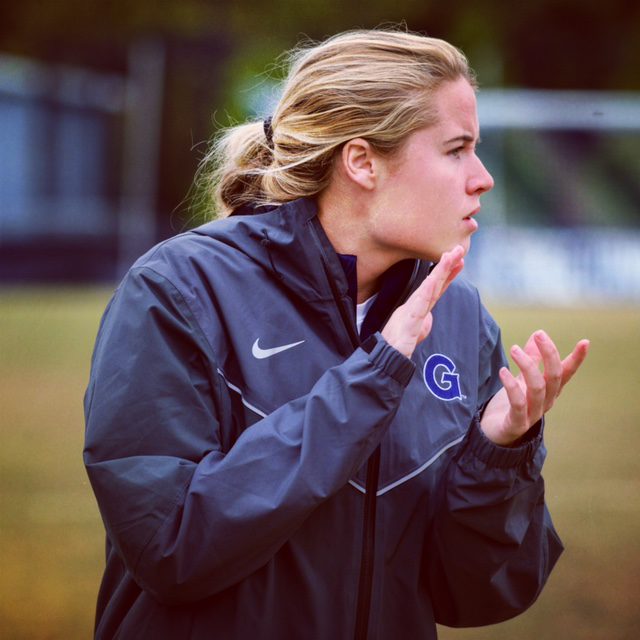 Female soccer coach clapping hands on soccer field
